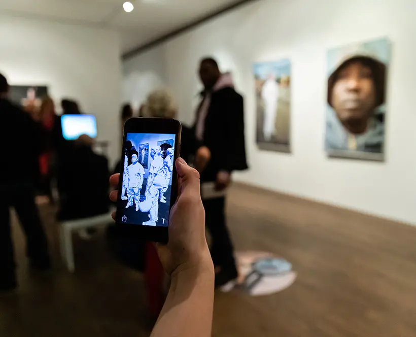 A vistor engages with an augmented reality artwork by Mohamed Bourouissa
