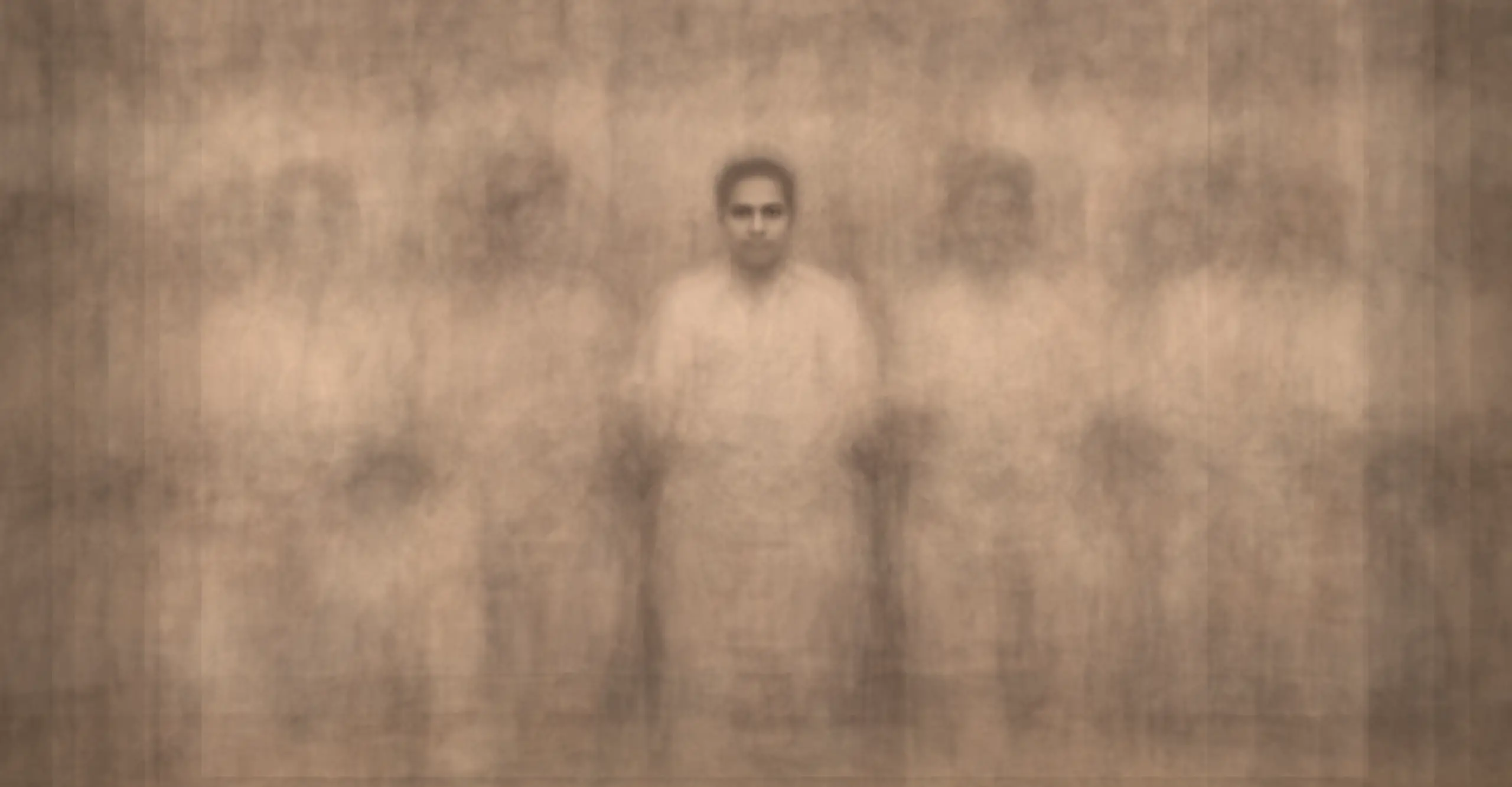 A composite of several sepia close-up photographs of a group of people posing in a South Asian photo studio. The image is ghostly other than the person in the centre's face.