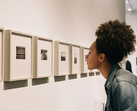 A person in a Gallery looking at framed photographs